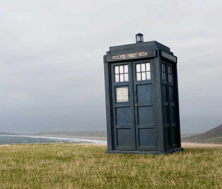 Y Tardis, Blwch Heddlu Doctor Who, ar bentir Bae Rhosili, gyda'r traeth a'r môr y tu ôl iddo