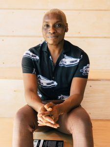 Laolu with his hands clasped and a book in front of him looking thoughtful.