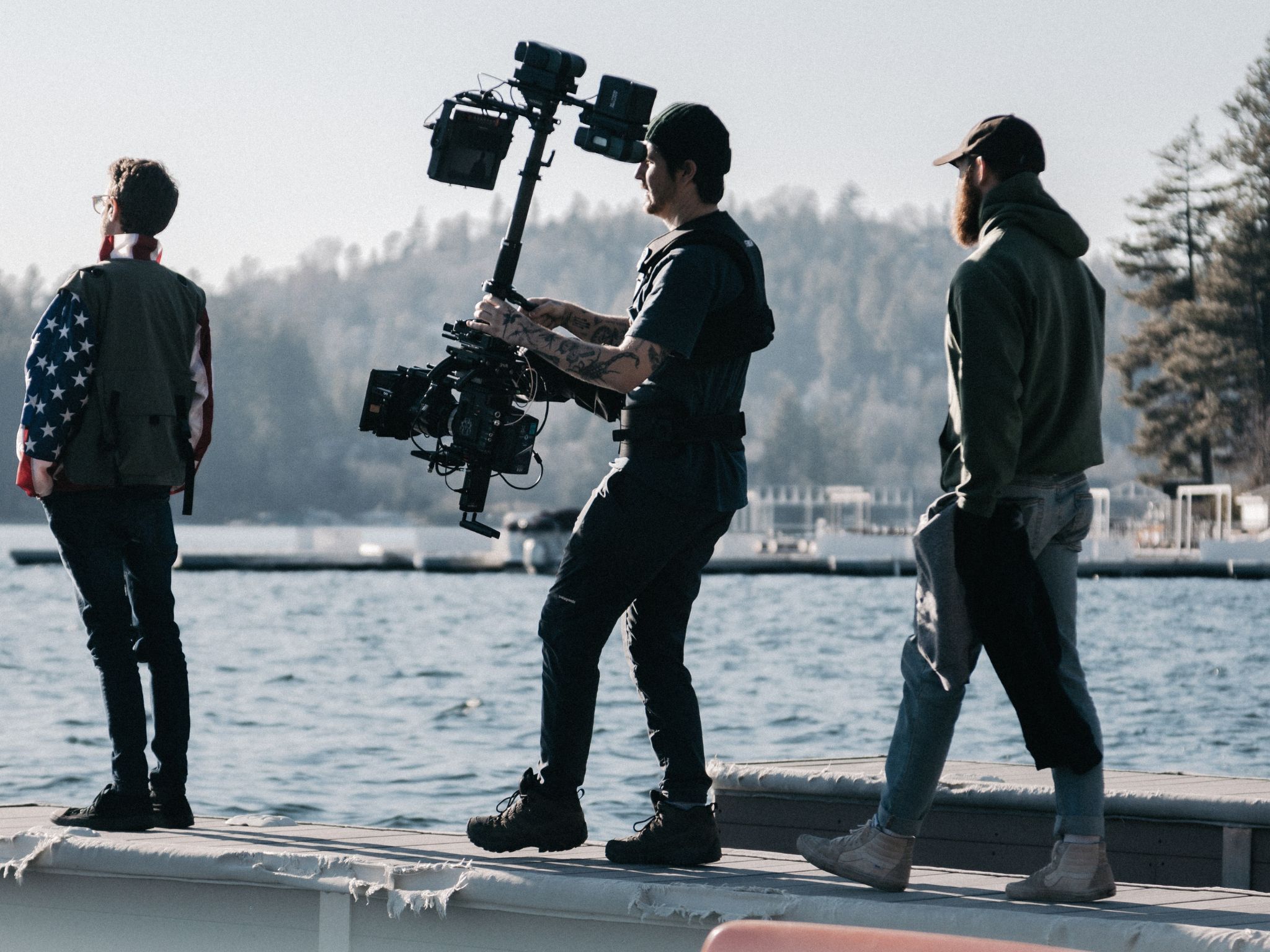 three people people staining near water holding filming equipment